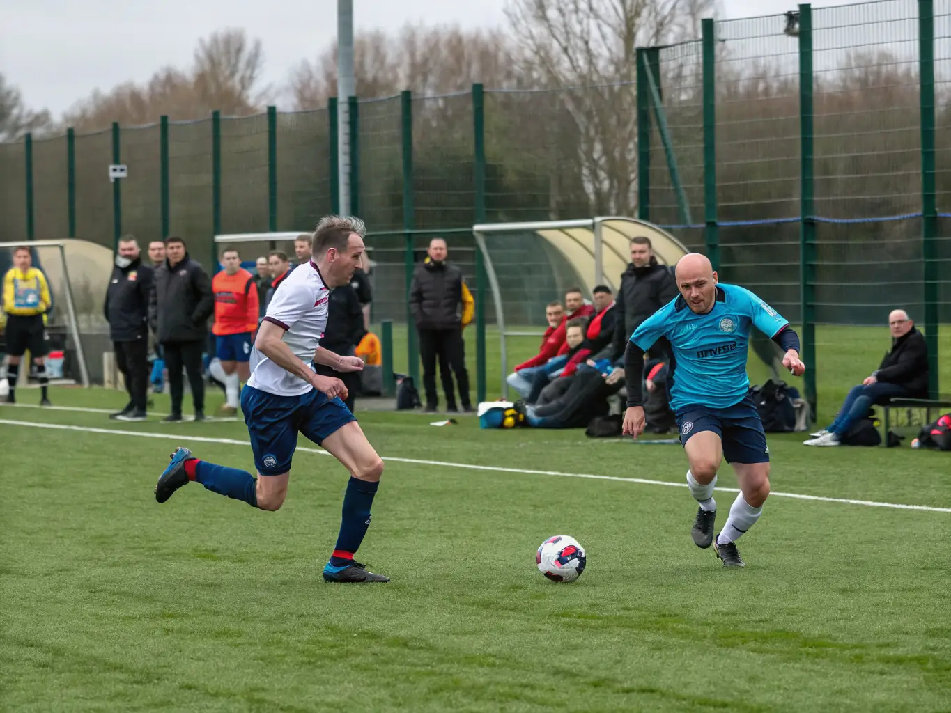An action shot of adults participating in a competitive football match, demonstrating skill, strategy, and camaraderie.
